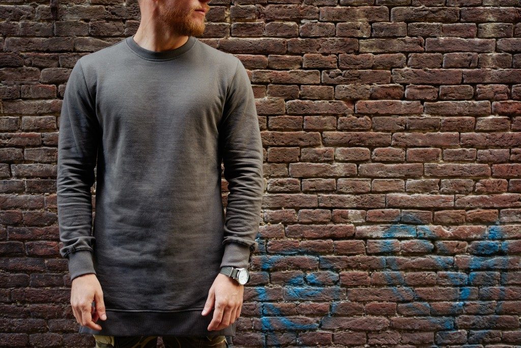 man wearing a black long sleeve shirt with brick walls as the background