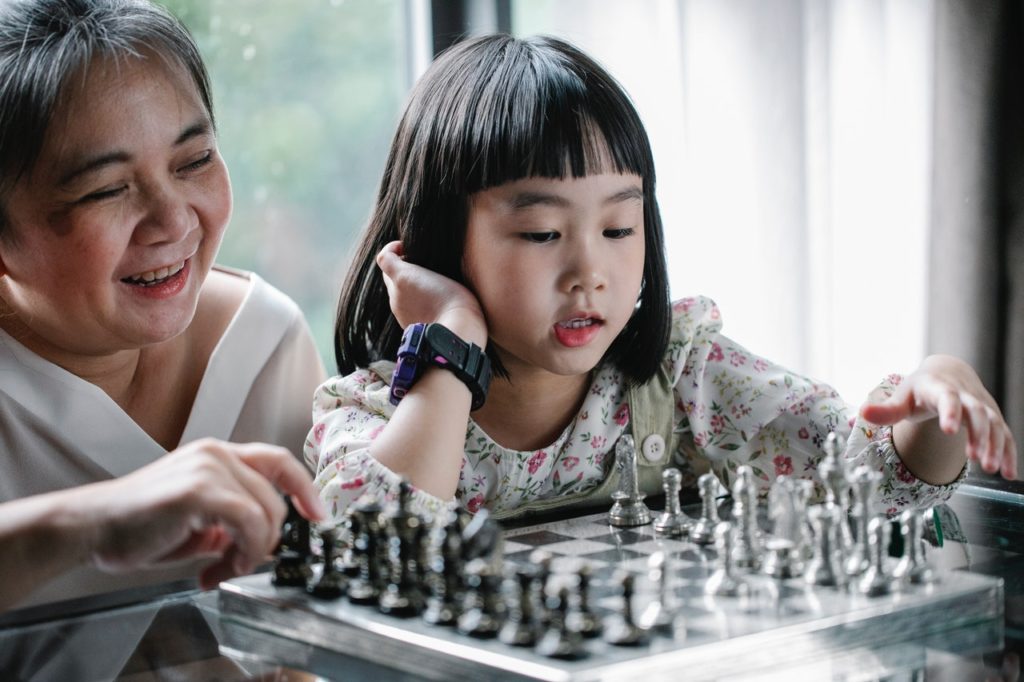 kid playing chess with her mother