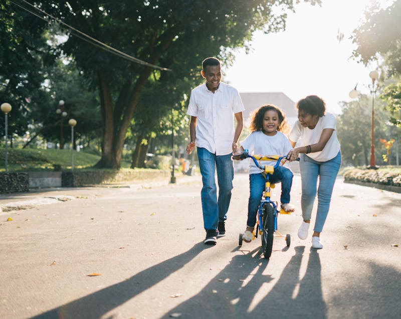 parents teaching their child how to ride a bicycle